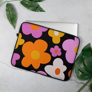 May include: A black laptop sleeve with a colorful retro floral pattern. The flowers are orange, pink, yellow, and white on a black background.