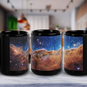 May include: Three black coffee mugs with a colorful nebula image printed on them. The image shows a swirling cloud of gas and dust with stars scattered throughout.