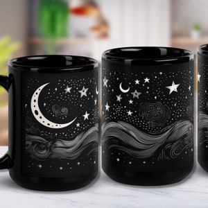 May include: Black ceramic mug featuring a celestial design with a crescent moon, stars, and flowing lines. The white illustrations contrast against the dark background. The mug has a large handle and a capacity of approximately 15 ounces.