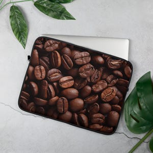 Könnte beinhalten: Eine Laptop-Hülle mit einem Nahaufnahmebild von gerösteten Kaffeebohnen. Die Bohnen sind braun und haben eine satte, dunkle Farbe.