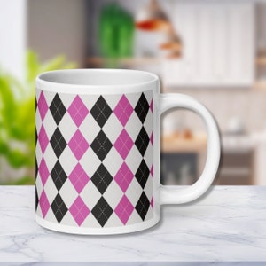 May include: White ceramic mug with a pink, black, and white argyle pattern.