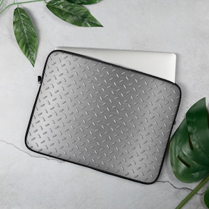 May include: A silver laptop sleeve with a diamond plate pattern. The sleeve is made of a durable material and has a zipper closure.