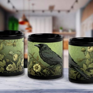 May include: Three black ceramic mugs with a design of a black crow perched on a branch with green leaves and white flowers. The design is reminiscent of vintage botanical illustrations.