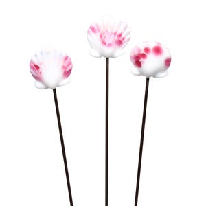 May include: Three decorative seashell-shaped objects on dark brown stems. The shells are white with pink accents, and the stems are thin and straight. The objects are arranged against a white background, suggesting a craft or decorative item.