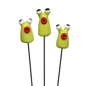 May include: Three whimsical, lime green alien-like garden stakes with large, googly eyes and red circular accents. Each stake is mounted on a dark brown metal rod, perfect for adding a playful touch to any garden or plant pot.