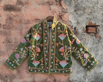 Puede incluir: Chaqueta bordada verde oliva con motivos florales en tonos rosa, naranja y morado. La chaqueta tiene cuello alto y está forrada con tela a rayas. El bordado está detallado con hilo dorado.