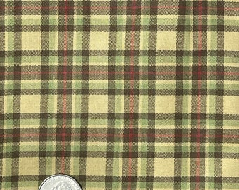May include: A close-up of a beige fabric with a plaid pattern in shades of green, brown, and red. A US quarter is placed on the fabric for scale.