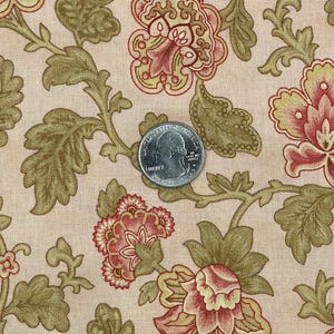 May include: Close-up of floral fabric with a quarter coin for scale. The fabric features a repeating pattern of large, stylized flowers in shades of red, yellow, and green on a beige background. The quarter coin is approximately 1 inch in diameter.
