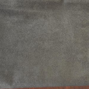 May include: A solid piece of dark gray fabric with a soft, matte, and slightly fuzzy texture. The material displays a consistent, uniform color across the entire surface, showing a dense, short-pile finish that appears smooth and even throughout.