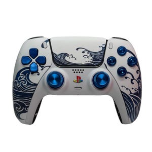 May include: A white PlayStation 5 DualSense controller with a blue and white wave design. The controller has blue buttons and blue thumbsticks.
