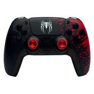 May include: Black and red video game controller with a spider logo. The controller has red thumbsticks and accents, with a white spider emblem on the top center. The right side features a red web-like design.