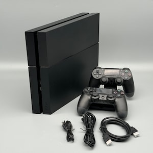 May include: A black PlayStation 4 console with two black controllers, and three black cables. The console is rectangular and has the letters "PS4" printed on the side. The controllers have multiple buttons and joysticks.