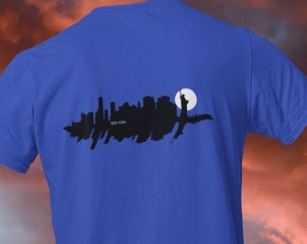 Könnte beinhalten: Ein königsblaues T-Shirt mit einer schwarzen Silhouette der New Yorker Skyline und der Freiheitsstatue. Die Skyline ist vor einem weißen Mond platziert.