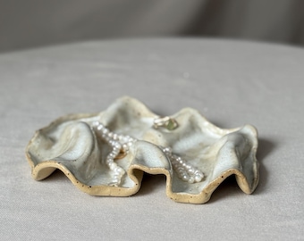 Handgefertigter Keramikuntersetzer in Wellenform – beigefarbener Ton mit braunen Sprenkeln, durchscheinende weiße Glasur