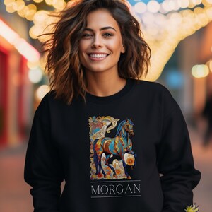 以下が含まれることがあります： カラフルな馬のデザインと「MORGAN」という名前が下に印刷された黒いスウェットシャツです。