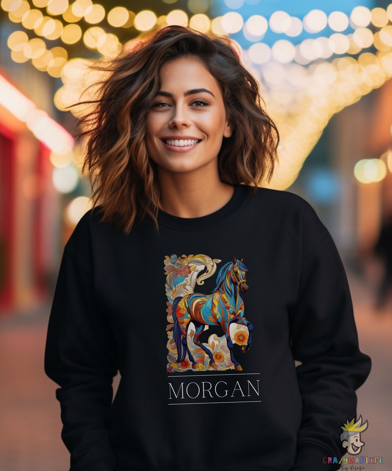 以下が含まれることがあります： カラフルな馬のデザインと「MORGAN」という名前が下に印刷された黒いスウェットシャツです。