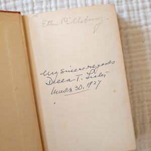 May include: Open book with handwritten inscription. The inscription reads "Etta Pillsbury" at the top, followed by "My sincere regards, Decca T. Selee, March 30, 1937." The pages are aged with a light tan color, and the binding is red.