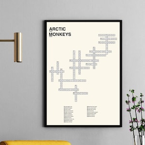 May include: A black framed poster with a crossword puzzle featuring the words "Arctic Monkeys". The poster is hanging on a grey wall above a yellow armchair and a small white side table with a vase of purple flowers.