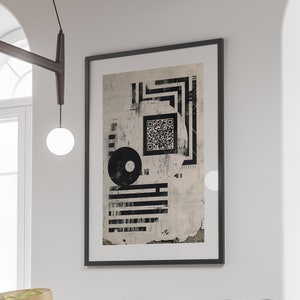 May include: A black dining table with two black chairs with woven cane seats. A framed black and white abstract print hangs on the wall behind the table. The print features a QR code and geometric shapes.