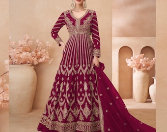 May include: A long, burgundy dress with gold embroidery. The dress has a V-neckline and long sleeves. The dress is flowing and has a long train.