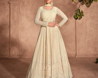 May include: A white floor-length gown with intricate embroidery and sequins. The gown has a fitted bodice and a flowing skirt.