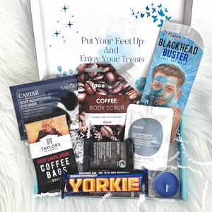 May include: A gift box filled with self-care items, including a coffee body scrub, a blackhead buster peel-off mask, a chocolate bar, and a candle. The box is decorated with blue butterflies and stars.