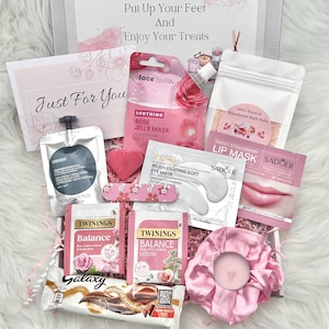 May include: A pamper gift box containing beauty and relaxation products. Items include a rose jelly mask, eye mask, lip mask, bath salts, tea bags, a chocolate bar, and a pink scrunchie with a candle. The box has the text "Put Up Your Feet And Enjoy Your Treats".