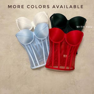 May include: Four different coloured corsets with a mesh overlay. The corsets are in white, light blue, red, and black. The text "MORE COLORS AVAILABLE WITH YOU" is at the top of the image.