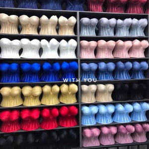 May include: A collection of strapless corset tops in various colors including red, blue, white, black, yellow, and pink, arranged on shelves. The text "WITH YOU" is visible in the center of the display among the rows of garments.