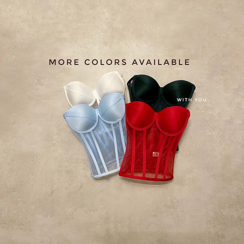 May include: Four different coloured corsets with a mesh overlay. The corsets are in white, light blue, red, and black. The text "MORE COLORS AVAILABLE WITH YOU" is at the top of the image.