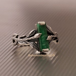 Könnte beinhalten: Ein silberner Ring mit einem grünen Edelstein, der in einem Blattdesign eingefasst ist.