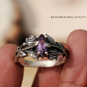 Könnte beinhalten: Ein silberner Ring mit einem violetten Edelstein, der in einem floralen Design eingefasst ist. Der Ring ist aus Sterlingsilber gefertigt und verfügt über einen Amethyst in Marquise-Form.