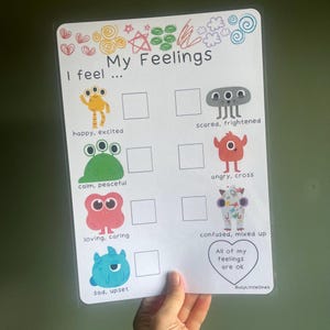 May include: A laminated My Feelings chart featuring colorful monster illustrations with corresponding emotion labels like happy, scared, and angry. The sheet includes blank squares for tracking and a heart graphic with the text All of my feelings are ok.