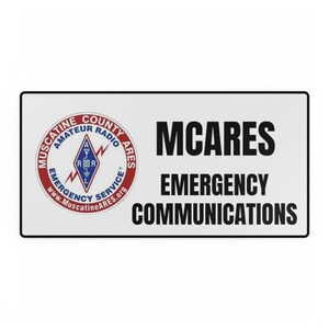 May include: White sign with black text that reads "MCARES EMERGENCY COMMUNICATIONS". A red, white, and blue logo is in the top left corner that reads "Muscatine County Amateur Radio Ares Emergency Service www.MuscatineARES.org"
