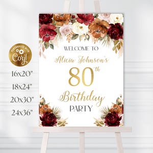 Puede incluir: Un letrero blanco sobre un caballete con arreglos florales y texto dorado. El letrero dice "Bienvenida a la fiesta de cumpleaños número 80 de Alicia Johnson". Tamaños disponibles: 40,6x50,8cm, 45,7x61cm, 50,8x76,2cm y 61x91,4cm.