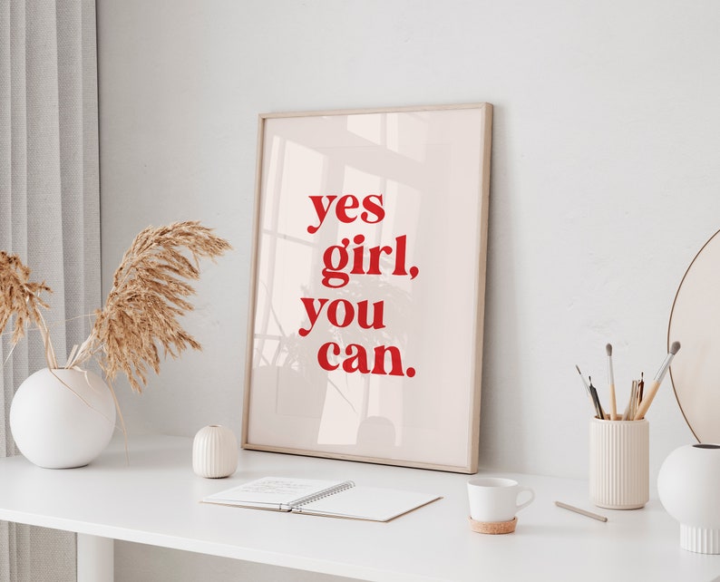 May include: A framed print with a white background and red text that reads "yes girl, you can."