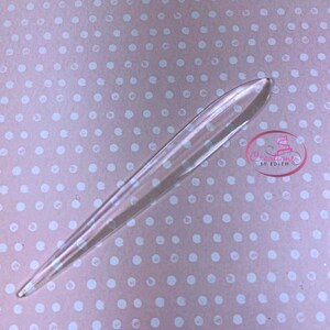May include: A clear plastic cake decorating tool shaped like a long, thin blade with a pointed tip.