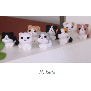 May include: A collection of handmade crochet cat figurines in various colors, including white, black, gray, and brown. Each cat has detailed features and is posed in a sitting or lying down position. The text "My Kitties" is at the bottom.