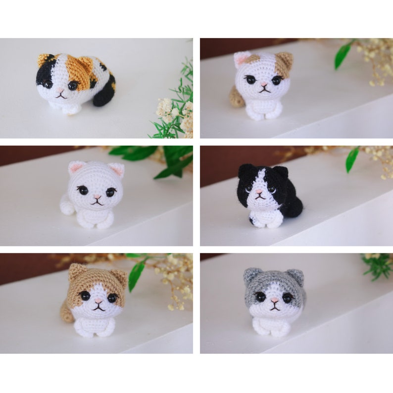 May include: A collection of six crocheted cat figurines in various colors. The cats are white with patches of black, orange, gray, and tan. Each cat has a detailed face with black eyes and a small, embroidered nose. The figurines are displayed on a white surface.