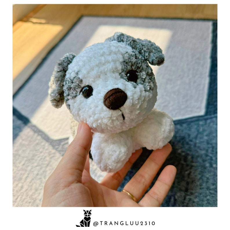 May include: A small, white and gray crocheted dog toy with brown eyes and a brown nose.
