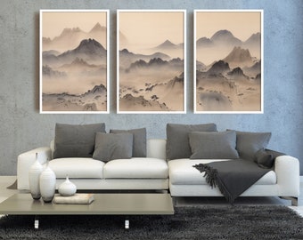 Puede incluir: Tres impresiones enmarcadas de una pintura de acuarela de una cordillera con un fondo brumoso. Las impresiones están colgadas en una pared gris sobre un sofá blanco con almohadas y una manta grises.