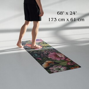 May include: A floral yoga mat, 68" x 24", featuring a dark background with a vibrant pattern of pink, orange, and purple flowers. The mat is rectangular and appears to be made of a flexible material.