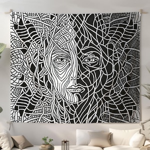 May include: Black and white tapestry featuring a stylized portrait of a face. The artwork is divided into two halves, one in white lines on a black background and the other in black lines on a white background. The tapestry is hanging on a wall.