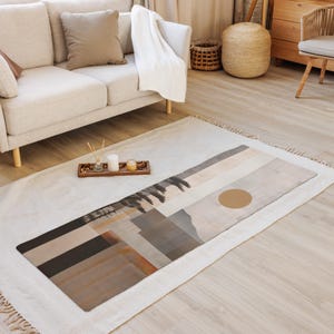 May include: A rectangular yoga mat with a landscape design in shades of brown, gray, and beige. The mat features a large, circular accent and a geometric pattern. The mat is placed on a white rug in a living room setting.