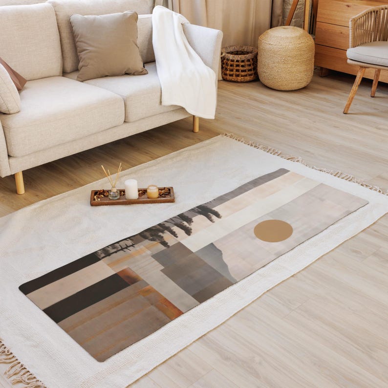 May include: A rectangular yoga mat with a landscape design in shades of brown, gray, and beige. The mat features a large, circular accent and a geometric pattern. The mat is placed on a white rug in a living room setting.