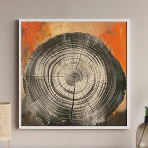 May include: A framed abstract painting of a tree trunk cross-section. The painting features a circular pattern of concentric rings in shades of black, white, and gray, with a hint of orange in the background.