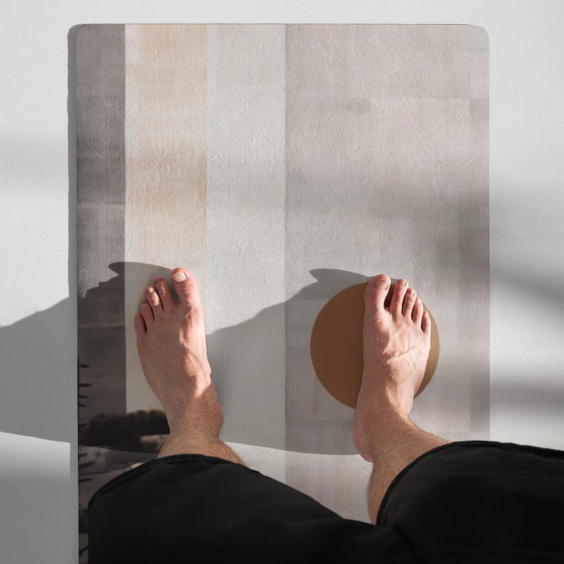 May include: A yoga mat with vertical stripes in shades of beige, gray, and white. A person's bare feet are positioned on the mat, with one foot resting on a brown circular object.