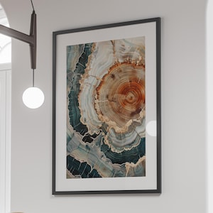 May include: Framed art print featuring a detailed cross-section of a tree trunk. The artwork showcases concentric rings in shades of brown, beige, and teal, creating a natural, abstract design. The print is encased in a black frame, suitable for home decor.