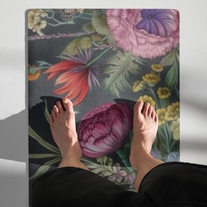 May include: A floral yoga mat featuring a dark background with large, colorful flowers in shades of pink, red, purple, and yellow. The mat has a detailed botanical design.