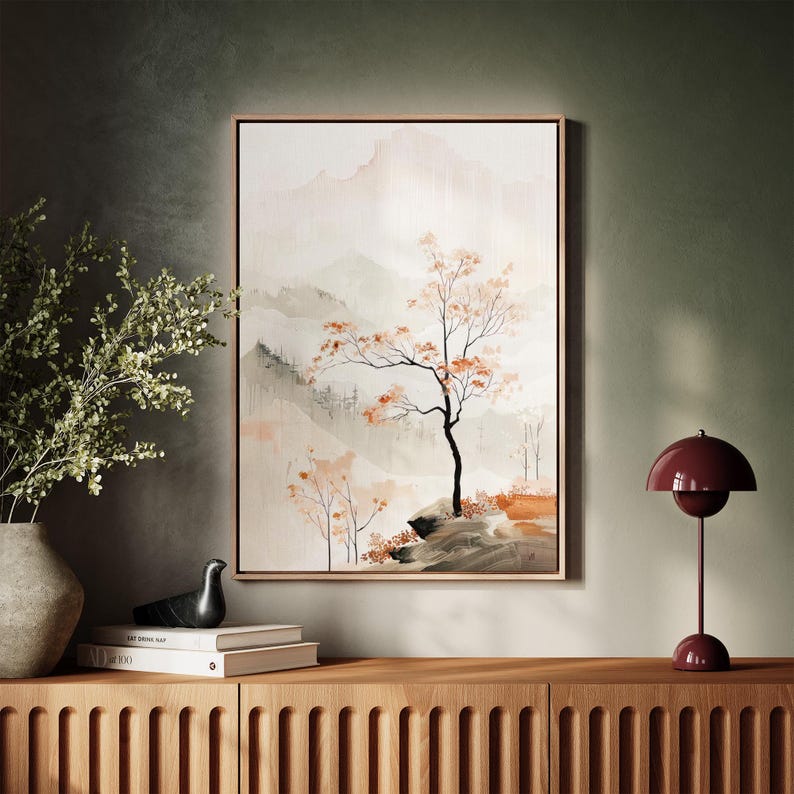 May include: A framed watercolour painting of a tree with orange leaves in a misty mountain landscape. The painting is on a wooden shelf with a lamp and a bird figurine.